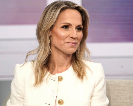 a woman with wavy blonde hair, a cream jacket, and a slight smile